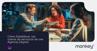 Cómo establecer los costos de servicios de una agencia digital Equipo de trabajo en reunión analizando estrategias con laptop y tablet en oficina moderna