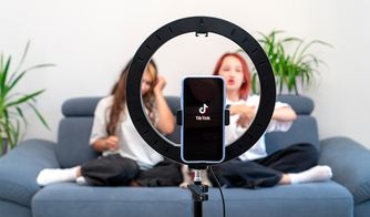 El auge de los creadores de contenido en TikTok Teléfono grabando un video de TikTok frente a dos jóvenes