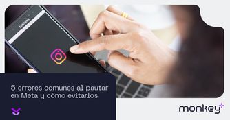 5 errores comunes al pautar en Meta y cómo evitarlos Persona usando aplicación de Instagram en un teléfono móvil sobre un teclado de laptop
