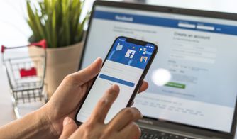 Inicio de sesión en Facebook desde móvil Usuario iniciando sesión en Facebook desde su celular frente a laptop