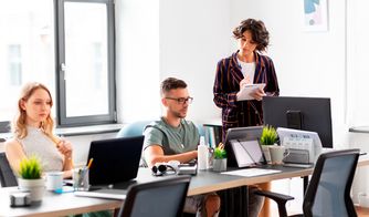 Trabajo en equipo dentro de una agencia digital Personas trabajando en una oficina moderna con computadoras y plantas