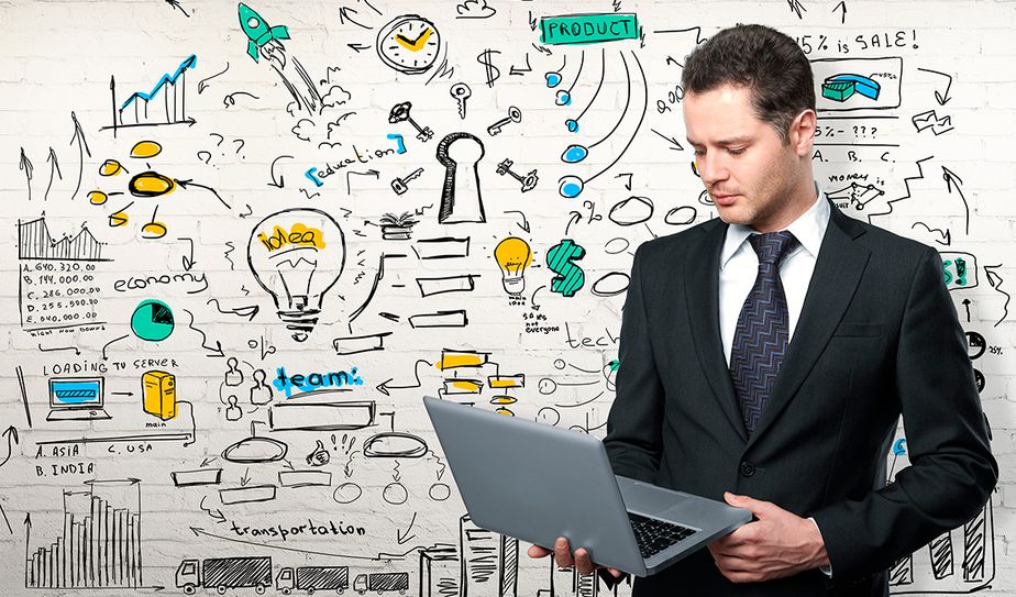 Ejecutivo con laptop frente a mural de ideas y gráficos
